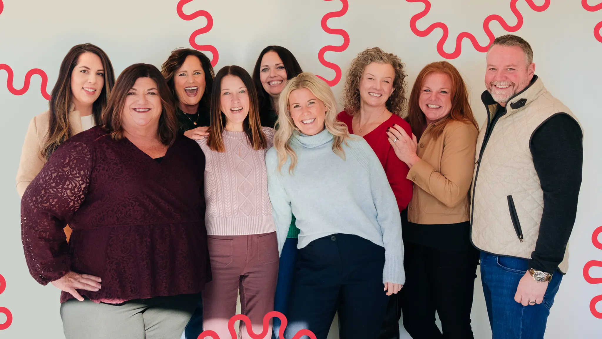 A group of people, the MyStaff team, embracing each other and pose for a photo against a white wall. They are smiling and laughing. Natural light floods the room.